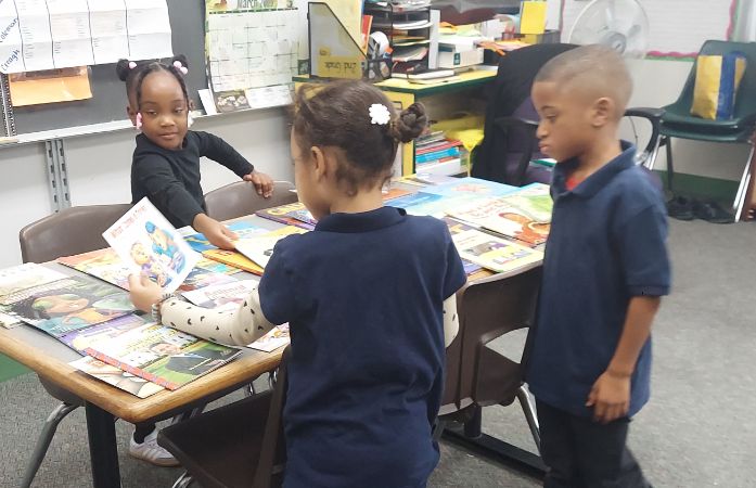  Three students standing around a table looking at books